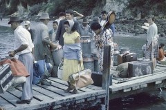 People with luggage and supplies gathered at the Matakana Island wharf.